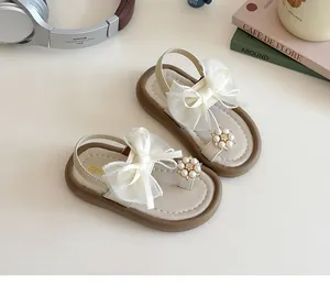 Detail of girls' sandals with soft bow and pearl flower on a warm aesthetic background