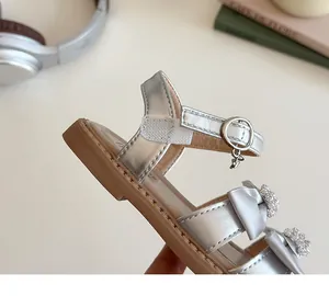 Detail van zilveren meisjessandalen met strass-strikken en parelster-bedeltjes