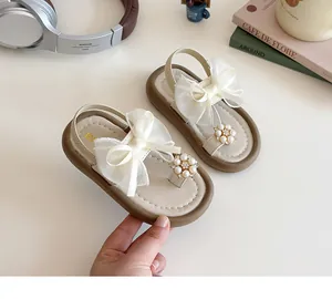 Close-up of girls summer sandals featuring pearl rhinestone flower and organza bow detail