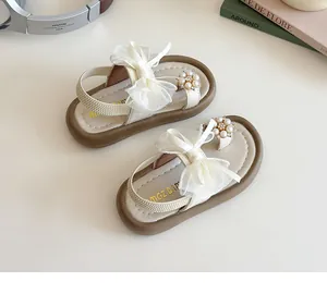 Detail of girls' cream sandals with soft sole, mesh bow, and pearl toe ring design