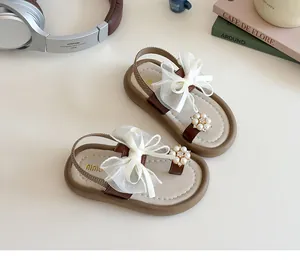 Detail of girls princess sandals with pearl flower and large white lace bow decoration