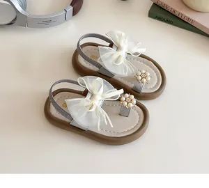 Detail of girls' sandals featuring large organza bows and delicate pearl flower accents