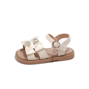 Beige meisjessandalen met strass-strikken, enkelbandje en een klein klokje als detail