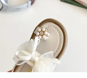 Close-up of girls sandals featuring a white organza bow and pearl rhinestone floral detail