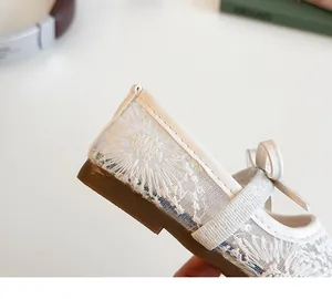 Gros plan sur la broderie en dentelle blanche et le nœud de ces chaussures Mary Jane
