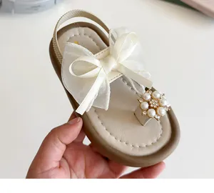 Detail of baby girl sandals featuring a mesh bow and pearl sunflower buckle on ivory straps