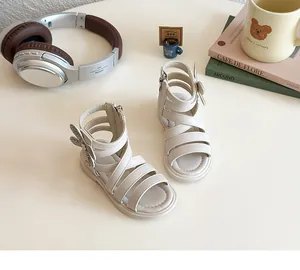 Detail of girls' cream gladiator sandals featuring rhinestone butterfly wing accents and side zipper