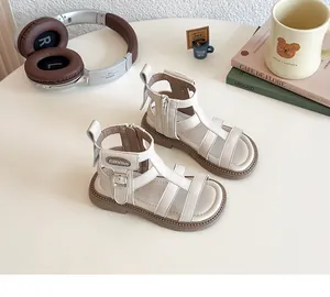 Detalle de sandalias romanas crema para niña con cremallera lateral y cierre de hebilla