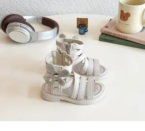 Detail of girls beige gladiator sandals with rhinestone bow and cute cat ear design