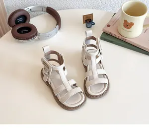 Detalle de sandalias gladiador blanco crema para niña con correas y hebilla de plata