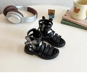 Detail of girls' black gladiator sandals with rhinestone bow and side zipper