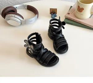 Detail of girls' black gladiator sandals featuring rhinestone bow accents and cross straps