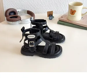 Detalle de sandalias romanas negras caladas para niña con correa alta y cremallera posterior