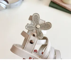 Detail of girls' roman sandals featuring rhinestone flower and silver metal studs
