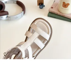 Primer plano de sandalias crema para bebé con correas trenzadas y cremallera trasera