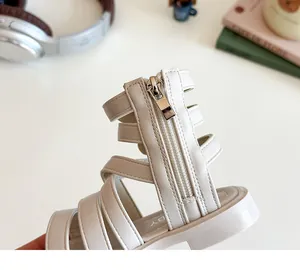 Detailed view of the silver heel zipper and stitching on beige Roman sandals for girls