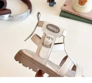 Detalle de sandalias romanas crema para niñas con hebilla de metal y tiras suaves