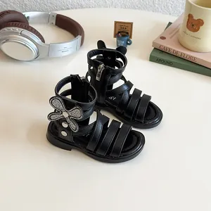 Girls black gladiator sandals with glitter bow and silver studs in lifestyle setting