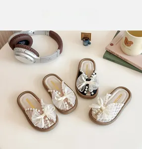 Détail de sandales fille avec nœuds, perles et dentelle en maille dans un décor chaleureux