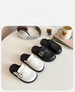 Dettaglio della texture in pelle opaca e fibbie argentate sui sabot da bambina
