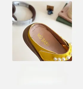 Gros plan de l'intérieur d'une sandale enfant en cuir jaune avec perles et logo