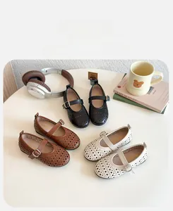 Three pairs of hollow Mary Jane shoes for girls displayed on a table with lifestyle props