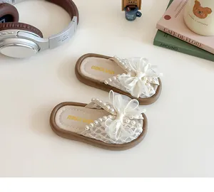 Détail de sandales pour filles avec dentelle, nœuds blancs et ornements en perles
