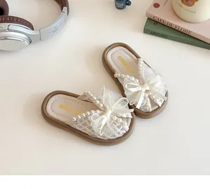 Détail de sandales beiges pour filles avec nœud en dentelle et perles décoratives