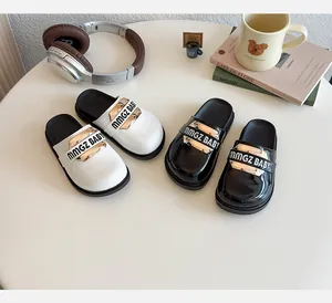 Dettaglio delle scarpe basse per bambina in bianco e nero con accenti dorati e lettere