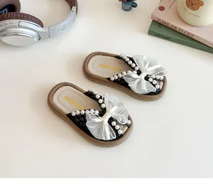 Détail de mules pour filles avec nœud en tulle blanc et ornements de perles
