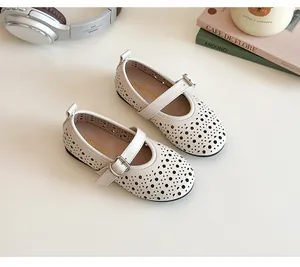 Detail view of white girls' Mary Jane shoes with perforated geometric patterns and metal buckle