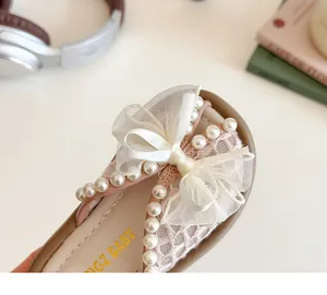 Détail de sandales roses pour filles avec grand nœud en mesh et perles blanches sur le bout