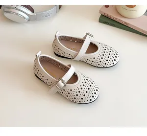 Detail of white girls' Mary Jane shoes with laser-cut patterns and buckle strap detail