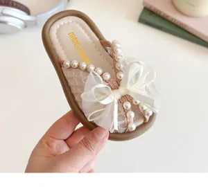 Détail de chaussons roses pour filles avec dessus en dentelle et nœud en organza