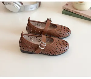 Detailed top view of brown leather Mary Jane shoes with perforated patterns on a white desk