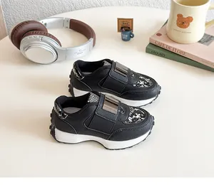 Détails de baskets noires pour enfants avec bandes velcro et boucles métalliques