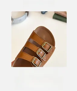 Détail de sandales en cuir marron avec boucles métalliques et semelle intérieure souple
