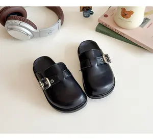 Vista dettagliata di sabot in pelle nera per bambina con fibbia argento e stile casual