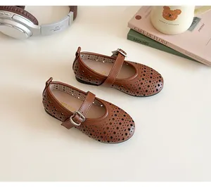 Detail of brown leather Mary Jane shoes with laser-cut hollow pattern and buckle strap