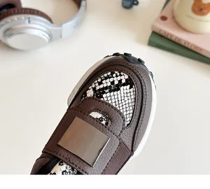 Détail de baskets filles avec cuir marron, imprimé serpent et accents métalliques