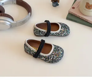 Detailed top view of sparkling sequin Mary Jane kids flat with elastic strap on a desk