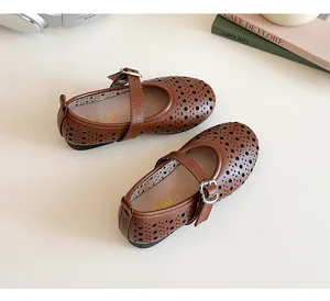 Detail of dark brown leather Mary Janes with decorative cut-outs and metal buckle strap