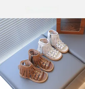 Détail de sandales bohèmes pour enfants avec franges, rivets et fermeture éclair en beige et marron