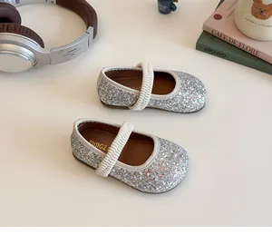 Macro detail of silver sequined Mary Jane shoes with white elastic strap and non-slip sole