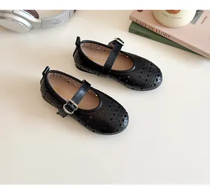 Close-up of black matte girls Mary Jane shoes with hollow punch pattern and heart buckle