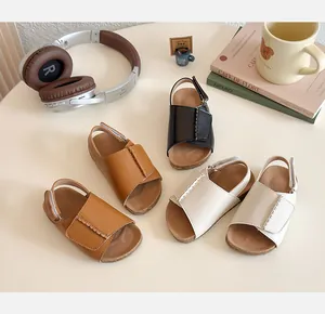 Detailed view of girls open-toe sandals with velcro straps in brown, black and beige