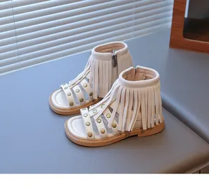 Détail de sandales bohèmes à franges avec clous dorés et fermeture éclair enfant