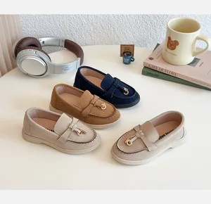 Flat lay of colorful children's suede loafers with metallic bow accents on a white table
