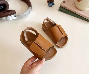 Detail of brown leather girl's sandals with woven straps and adjustable velcro heel