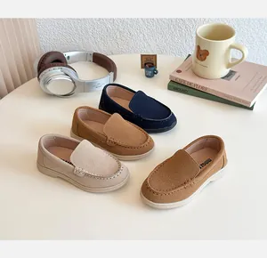 Mocassini per bambini in pelle scamosciata blu, marrone e beige con oggetti su tavolo bianco